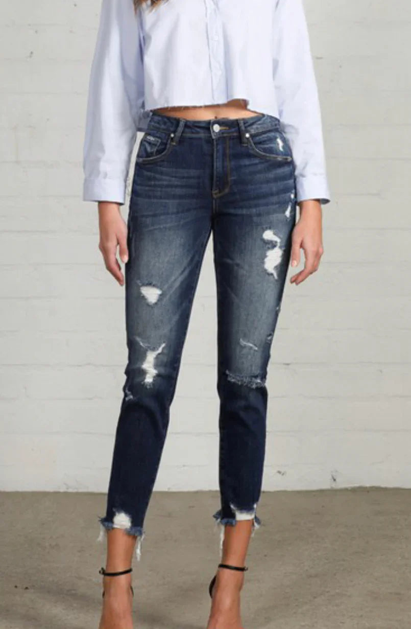 Distressed ripped jeans with frayed hems paired with a white crop top for casual western style