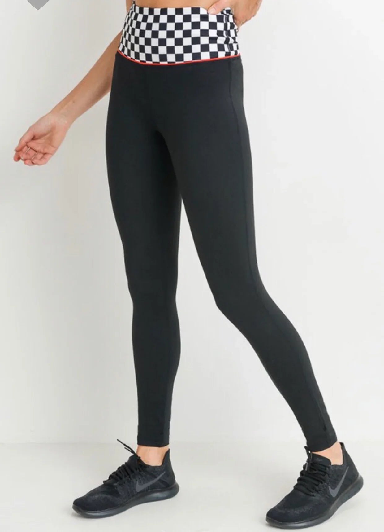 Black high-waisted leggings with checkered waistband, paired with black sneakers for casual wear.